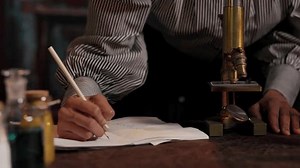 Woman from the Victorian era working with a microscope and making notations regarding her observations.