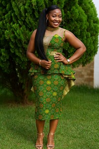 A fitted green Ankara dress with golden circular patterns, sculpted peplum detailing, and a sleek long ponytail — polished, vibrant, and beautifully shaped for a standout look. ✨ #ankarastyles | African Print Designer's