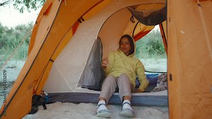 happy beautiful ukrainian Woman in orange camping tent admiring morning sunrise. Traveling camp lifestyle and alternative hotel room vacation concept. local traveling in Ukraine
