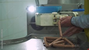 Food factory. Worker produces sausages on a automated food production equipment. Close up. Part of sausage production. 4k