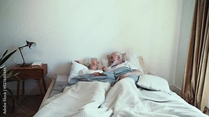 Elderly couple at home. Old woman and man having fun laughing in bed in the morning. Concept about third age and love