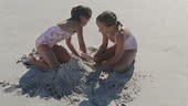 Girls making sand castle on beach. MS, TD, shaky, slow motion.