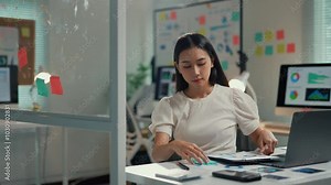 Young professional concentrating on tablet analysis while organizing colorful sticky notes in a modern office setting. Efficient multi tasking in a creative workspace