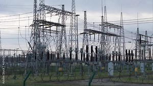 High-angle drone shots and ground-level perspectives unveil a transformer station against a backdrop of sunset clouds. The intricate tapestry of high-voltage poles, lattice structures, cables