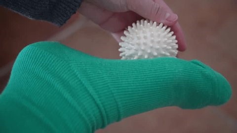 clip-4040138885-woman-plantar-fasciitis-uses-spiky-massage-her