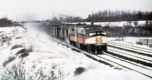 New Haven Railroad DER-3a ALCO PA-1 locomotive # 0775 & a DER-1 ALCO DL-109, are seen leading a passenger train in the snow along the Shore Line at an unknown location, mid 1950's, Mac Seabree Collection