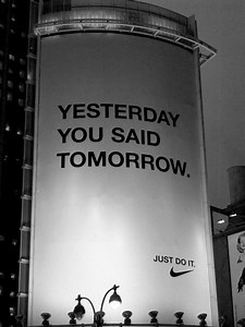 A minimalist and motivational shot of an open page from a dark paper journal. The text on the page, printed in a clean, bold, sans-serif, dark font, reads: