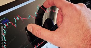 businessman pinch on the financial candles chart on his tablet with business news on a computer screen chart in the background