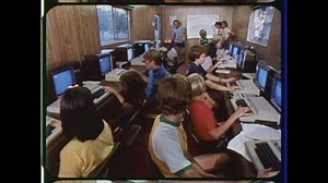1980 Indianapolis, IN. Young Adults in Computer Classroom. Kids listen to instructor while learing computer programming. 1980s fashion and style. 4K Overscan of Vintage Archival Newsreel Film