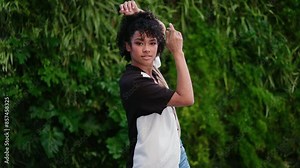 young woman dancing gracefully in slow motion, capturing fluidity and emotion of her movements.Her expressive dance against a backdrop of lush greenery highlights connection to nature and the art form