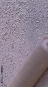 Worker applies pink paint to wall as part of buildings exterior refresh. Careful strokes ensure wall regains uniformity, enhancing visual appeal and preserving structures look