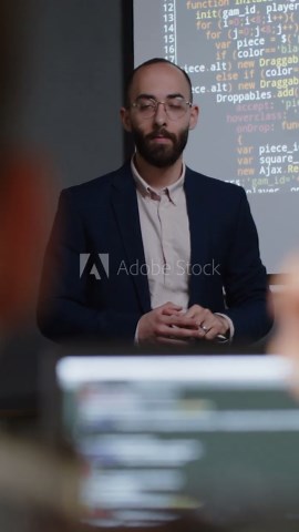 Medium vertical shot of anonymous college student raising hand to ask question at programming lecture, male teacher nodding, answering and demonstrating on code example on projector screen