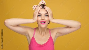 Amazed pretty pinup girl in yellow dress showing thumbs up and inviting gesture