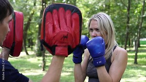 Beautiful woman boxing with a trainer. Portrait of a female boxer.