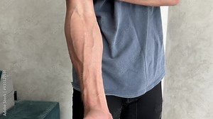 Athlete flexing biceps showcases prominent vascularity and well defined veins, highlighting strength and fitness