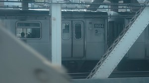 Looking out the window of a New York City subway train in motion seeing another train at same speed going over the Manhattan Bridge with the skyline in the background POV shot | Premium Stock Video Footage