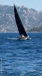Yacht sailing windward. Vertical video. A J-Class racing yacht in Aegean Sea in front of high mountains. Sailboat with a single mast and black sails. Excitement of a yacht race Marmaris offshore