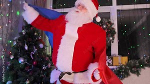 Cheerful Santa Claus with French flag in hands, dances, on festive Xmas background decorated with Christmas tree, tinsel and shimmering garlands. Happy New Year party. Close up.