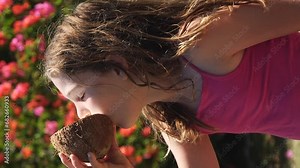 Cute, young girl drinking coconut milk or water from a shell - vertical