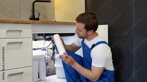 Plumber with white clean aqua filter. Serviceman change water filter. Installation of reverse osmosis water purification system