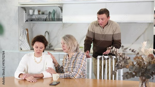 Family members quarreling in the kitchen and old woman trying to calm angry woman sitting at the table