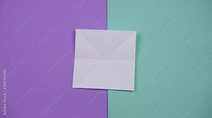 Process of creation origami bird in 4k stop motion animation. White sheet movement isolated on a colored background. Handmade and art concept