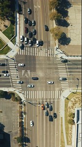 Vertical Screen: Vertical Aerial View of an Urban Intersection with Cars Moving and Waiting, Highlighting Multiple Crosswalks. The Scene Reflects the Bustling City Environment. 4K Footage.