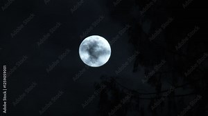 Cool blue full moon appears and disappears as dark clouds fill the night sky.
