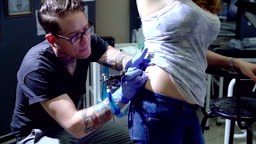 Woman receiving hip tattoo from tattoo artist. MS, pan down, slow...