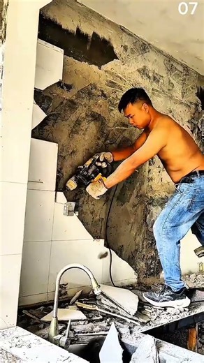 Removing wall tiles using power tool above kitchen sink area