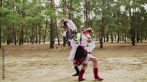 Young woman and man in traditional costumes are dancing Ukrainian national dance