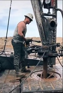Oil rig worker ”throwing the chain” (a dangerous method of connecting the drill pipes)