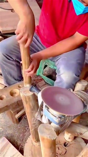 Smoothing and shaping a long wooden pole using a specialized rotating disc sander for woodworking