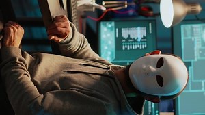 Vertical video: Masked scammer hacking computer network late at night, working on laptop and multiple monitors to steal IT information. Hacker with hidden identity breaking security server, cyber