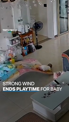 A baby rolled off her play mat after it was lifted off the ground by a strong wind that came through the windows of her home in Guangdong, China, on July 17. | TRT World