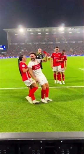 female referee stops play and signals a major penalty lifting a red card toward a male player