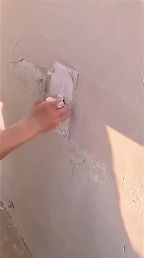 A person is smoothing damaged wall plaster using trowel