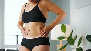 Woman compressing the skin on her stomach and sides checking for cellulite and excess subcutaneous fat