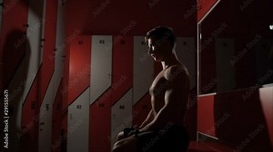 Sports man standing with towel and bag in the locker room at the gym. The athlete changes clothes in the locker room of the gym.