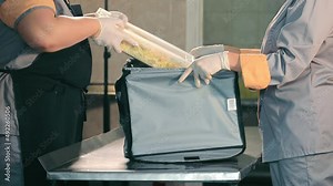 Packing food in a thermo bag. Workers in the kitchen dip hot food in containers in a thermal bag for further delivery. Food Delivery
