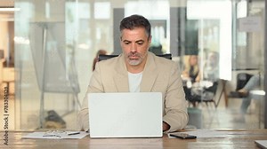Busy mature professional business man ceo looking at laptop working at desk. Serious middle aged executive manager investor using computer thinking on digital financial investing risks in office.