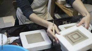 Woman s hands making concentric square pattern on pieces of clay. Locked down real time medium shot
