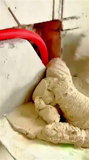 applying and smoothing thick white plaster or cement paste onto a wall corner during renovation