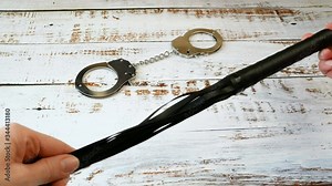 whip and handcuffs on a white wooden table, quarantine adult games, violent sexual games