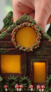 Butterscotch candies are perfect for creating glowing windows on a gingerbread house (or chocolate cookie house, in this case!) The printable supply list, recipes, and instructions to recreate this cozy log cabin cookie are available to my Cookie Art Club members. If you haven't joined yet, you can try it free for 7 days! #SweetAmbs #CookieArt #SummerCookies #LogCabinCookies #EdibleArt #CookieDecorating #CookieArtClub #GingerbreadHouse #CookieTutorial #BakingInspiration #SweetTreats #CookieScene