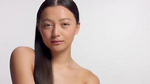 mixed race asian model in studio beauty shoot Model poses to a camera, straight hair combed to right side. Ideal skni and no makeup makeup Head and shoulders crop