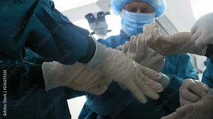 Directly below view of unrecognizable surgeons and assistants putting on medical gloves and getting ready for serious surgery
