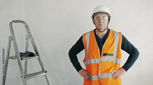 Male construction worker in safety uniform, hard hat and goggles on a construction site. Renovation of apartment concept.
