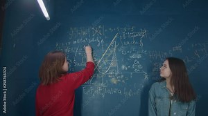 Girls school girls write on the blackboard a mathematical formula, talking and laughing. Students write in chalk on the wall, draw graphs. Teenagers are preparing for the exam. Slow motion, 4K