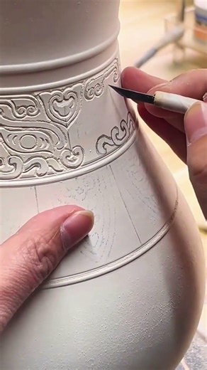 Hands carving swirling motifs on ceramic vase, crisp rhythm of morning pottery craft